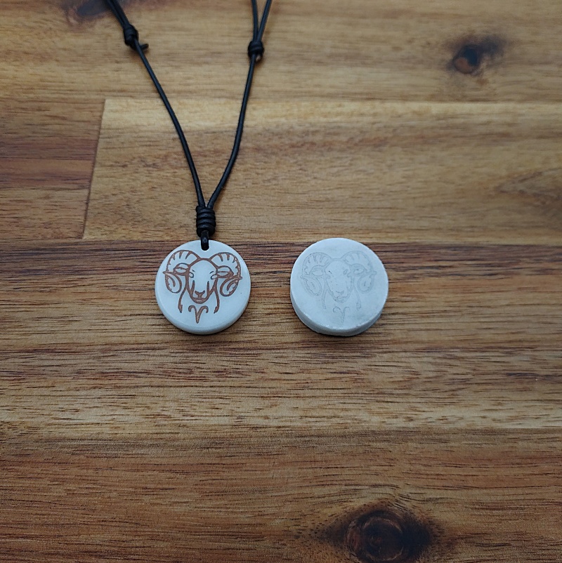 Travail en cours d'un pendentif et un terminé : un bélier en marbre blanc et cuivre