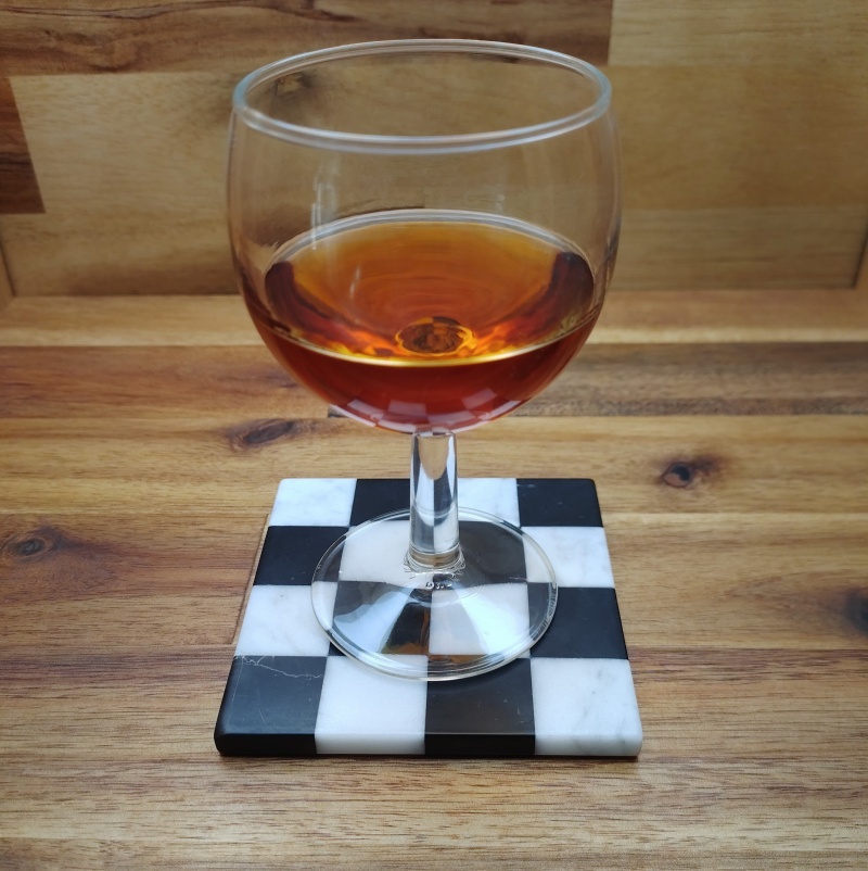 Verre sur son sous-verre damier, un objet d'art en marbre blanc et noir